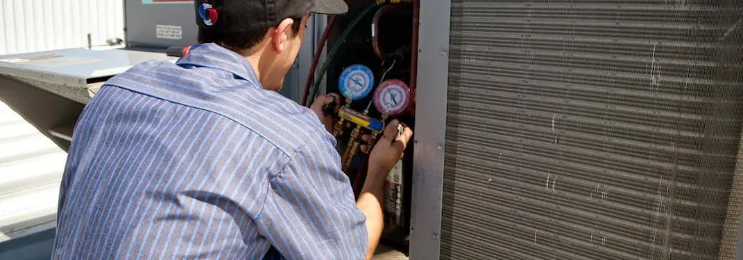 HVAC technician servicing a condenser unit in Zion